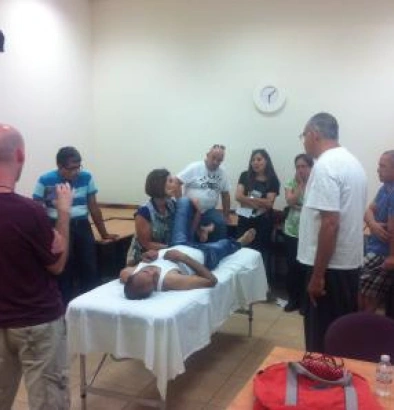חברי האיגוד במפגש לימוד, בתמונה ניתן לראות מטופל שוכב על המיטת עיסוי ועושים עליו הדגמה